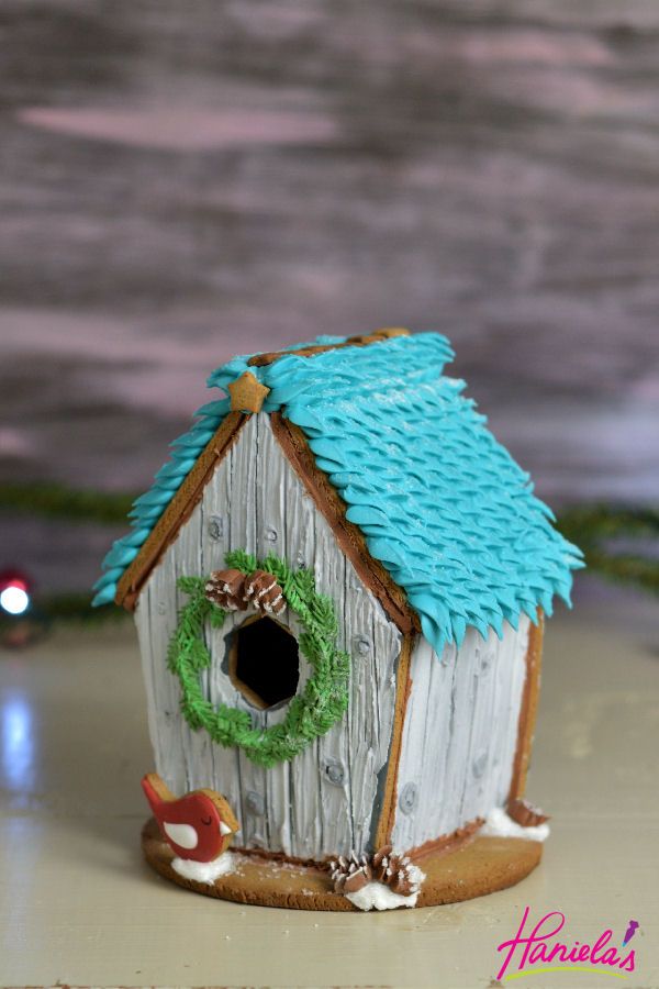 a birdhouse with a wreath on the roof and a green wreath hanging from it's side