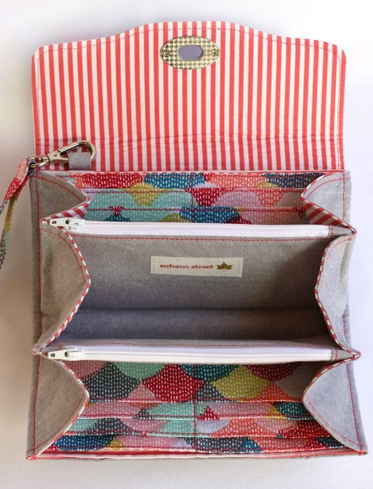 an open purse sitting on top of a white table next to a red and white striped bag