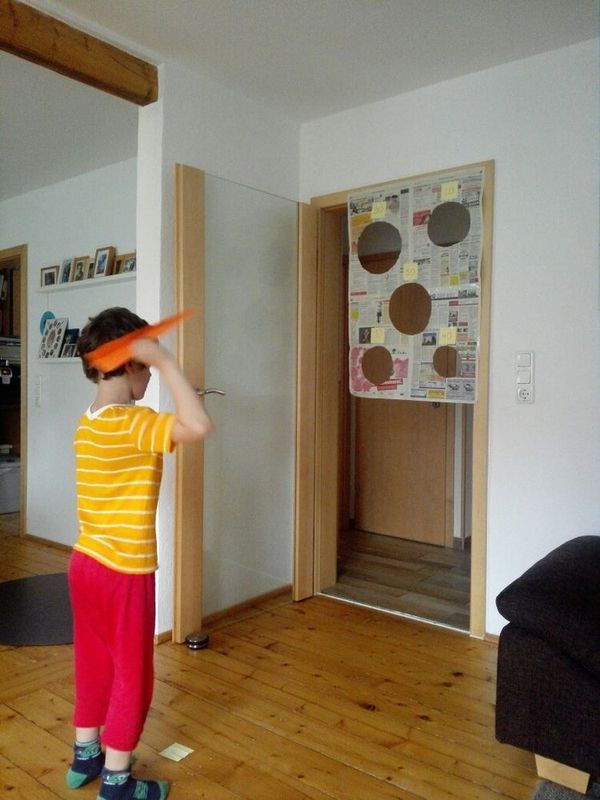 a young boy standing on top of a wooden floor holding an orange object over his head