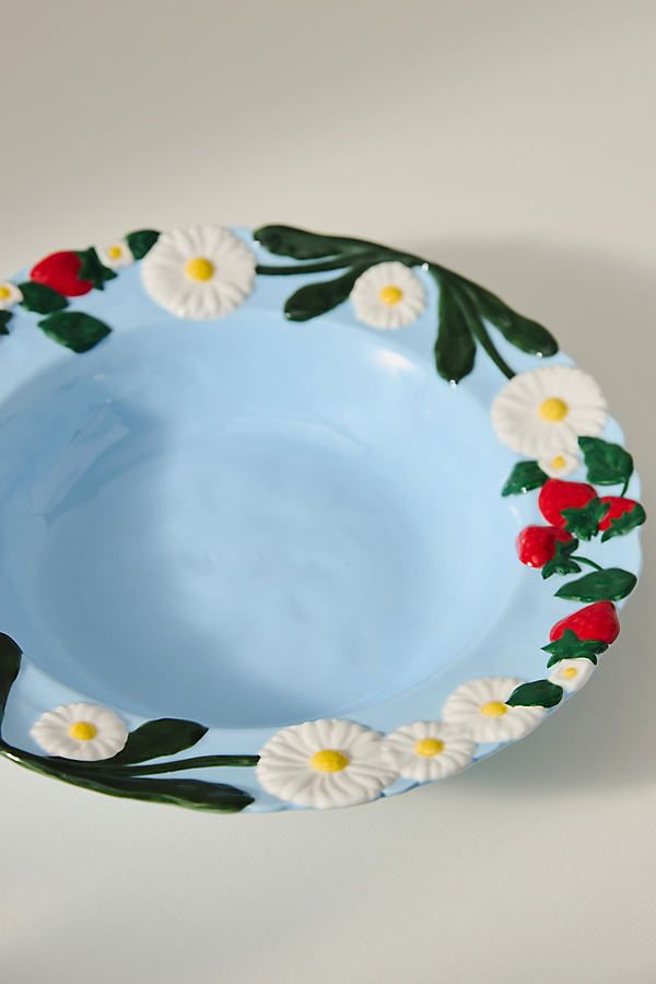 a blue bowl with white and red flowers on it