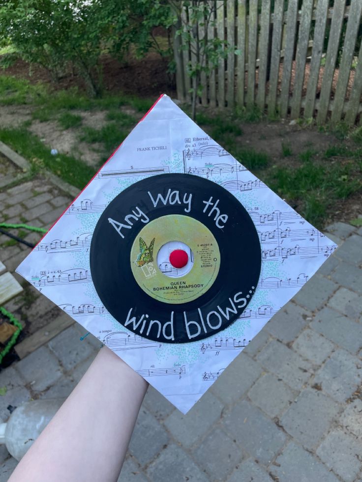 someone is holding up a record that says and way the wind blows