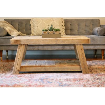 a wooden coffee table sitting on top of a rug in front of a gray couch