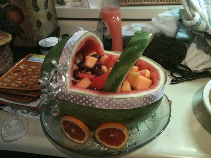 a watermelon bowl filled with sliced fruit on top of a counter next to other food