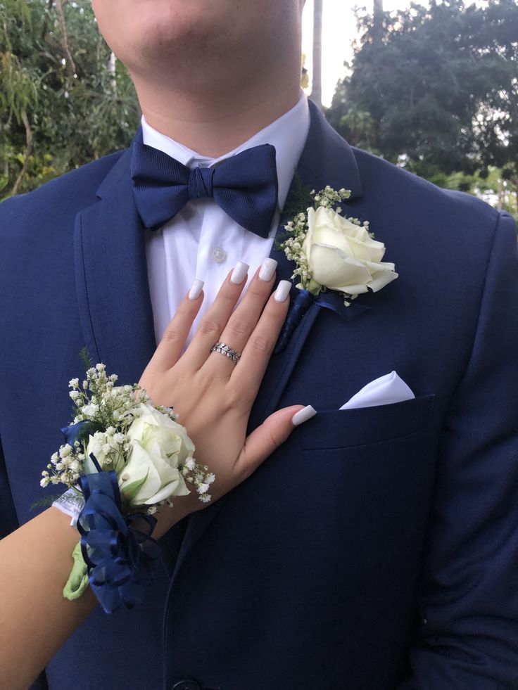 a man in a blue suit and bow tie with flowers on his lapel flower