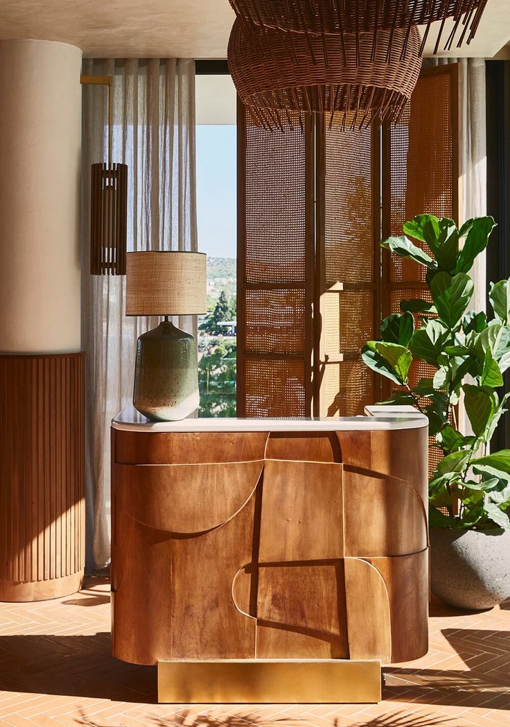 a large wooden cabinet sitting next to a lamp on top of a table in front of a window