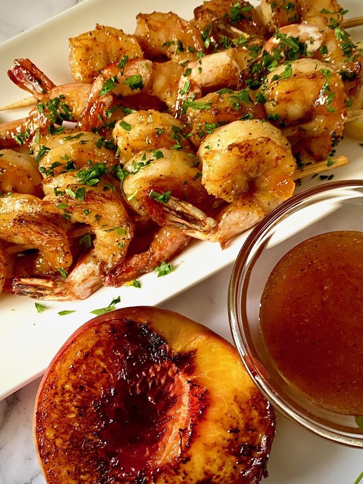 grilled shrimp and peaches on a plate with dipping sauce