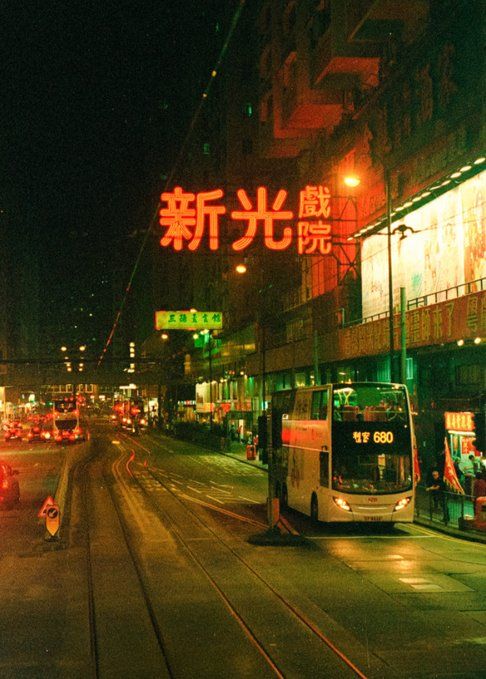 a city street filled with lots of traffic next to tall buildings and lit up neon signs