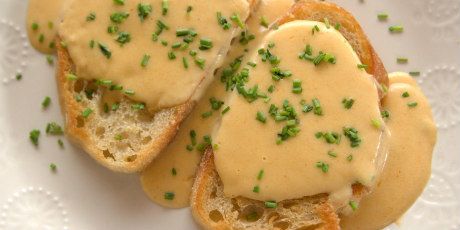 two pieces of bread topped with gravy and chives on a white plate