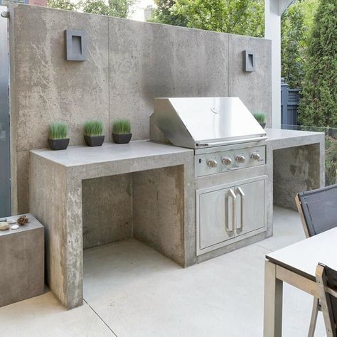 an outdoor kitchen with stainless steel appliances and potted plants on the outside wall,