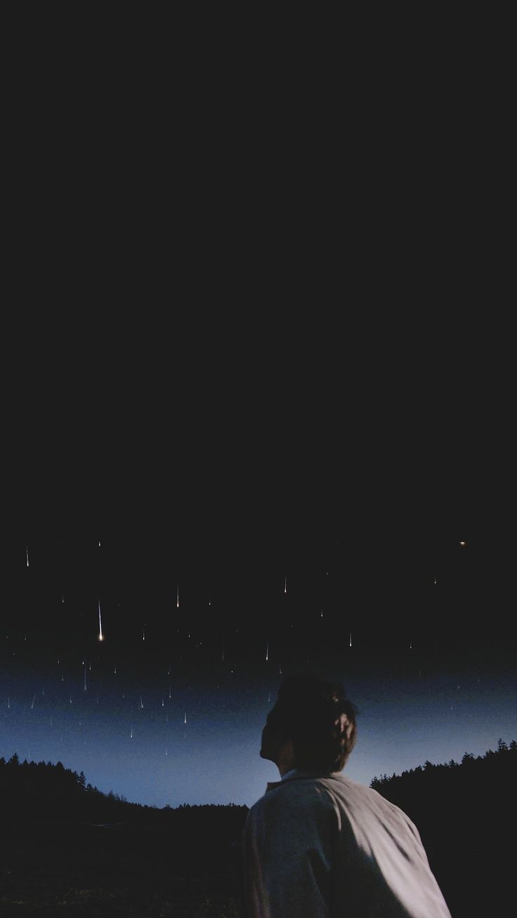 a man standing on top of a lush green field under a night sky filled with stars