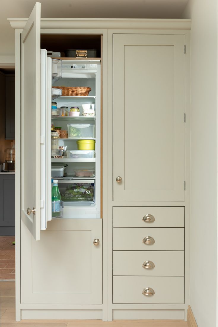 an open refrigerator with its door wide open in a kitchen area that is mostly white