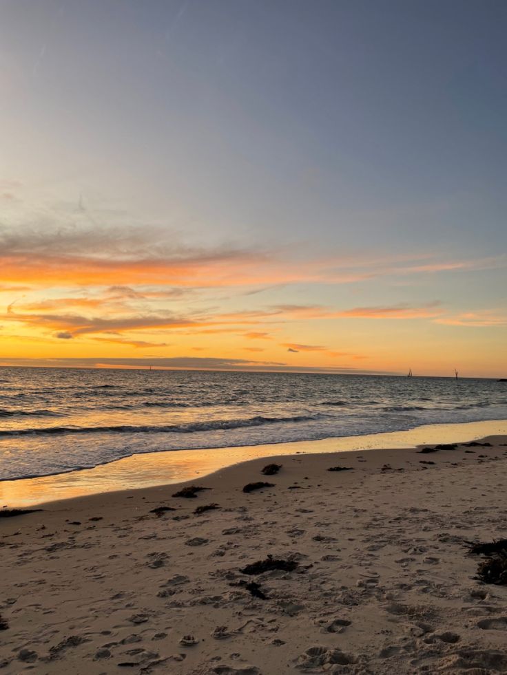 the sun is setting over the ocean and beach