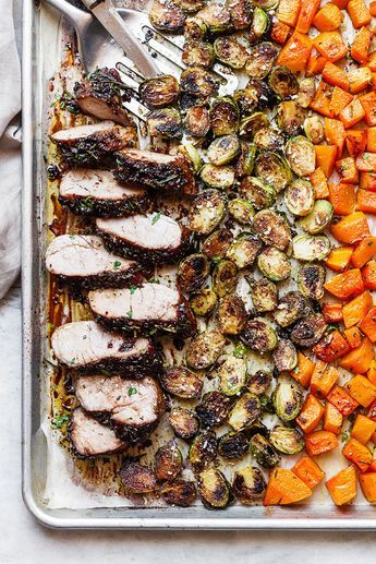 a tray filled with meat and vegetables next to a spatula on a white table