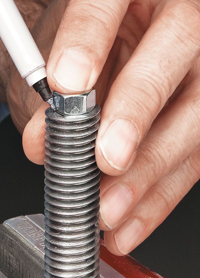 a man is working on some type of metal object with a screw in his hand