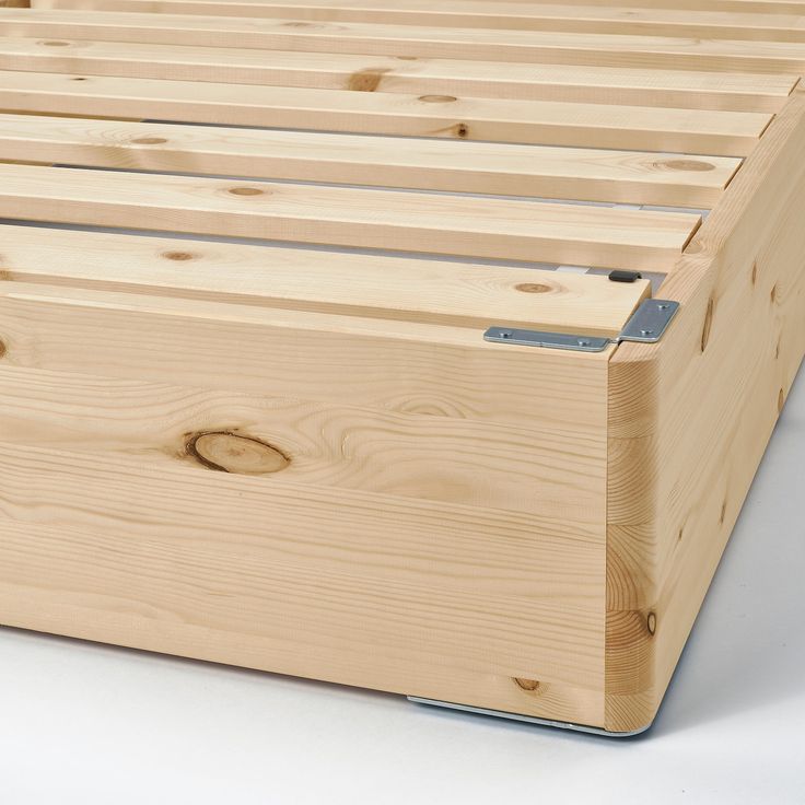 a wooden bed frame with no sheets on it and wood slats in the bottom