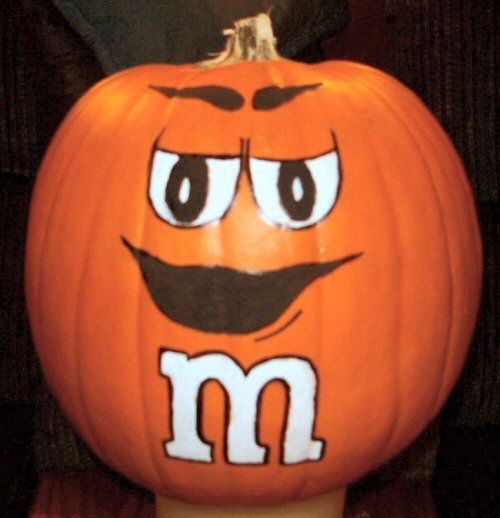 a close up of a pumpkin with the letter m painted on it's face