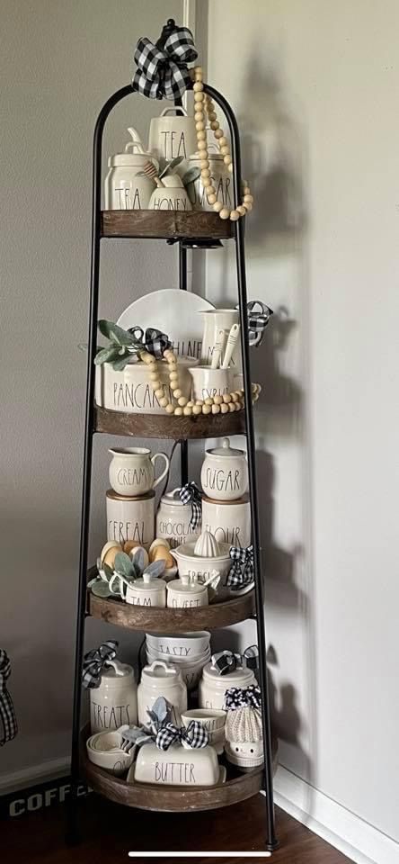 a three tiered tray with coffee mugs and plates on it in front of a wall