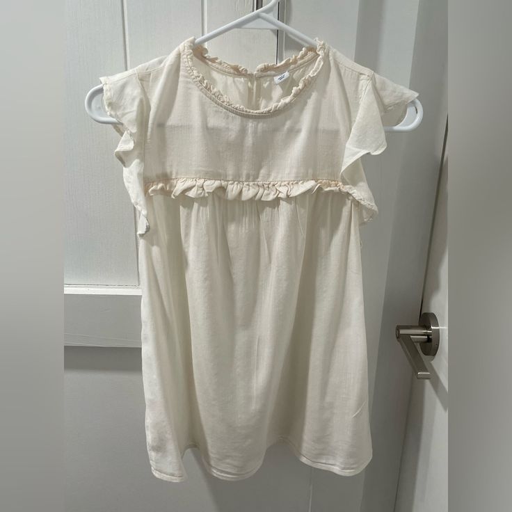 Old Navy Blouse. Size Xs. Light Cream Color. Has Cute Ruffled Details And Flowy Very Short Sleeves. Somewhat Sheer. Never Worn And In Flawless Condition! Approximate Measurements Lying Flat: Pit To Pit: 17” Length Shoulder To Bottom Hem: 22” Make An Offer! Beige Sleeveless Blouse For Daywear, White Ruffle Sleeve Top For Daywear, Beige Flowy Short Sleeve Blouse, Beige Sleeveless Blouse For Day Out, Flowy Cotton Tops With Lace Trim, Sleeveless Ruffled Blouse For Daywear, Flowy Beige Short Sleeve Blouse, Beige Ruffle Sleeve Tops For Brunch, Casual Sleeveless Blouse With Lace Trim