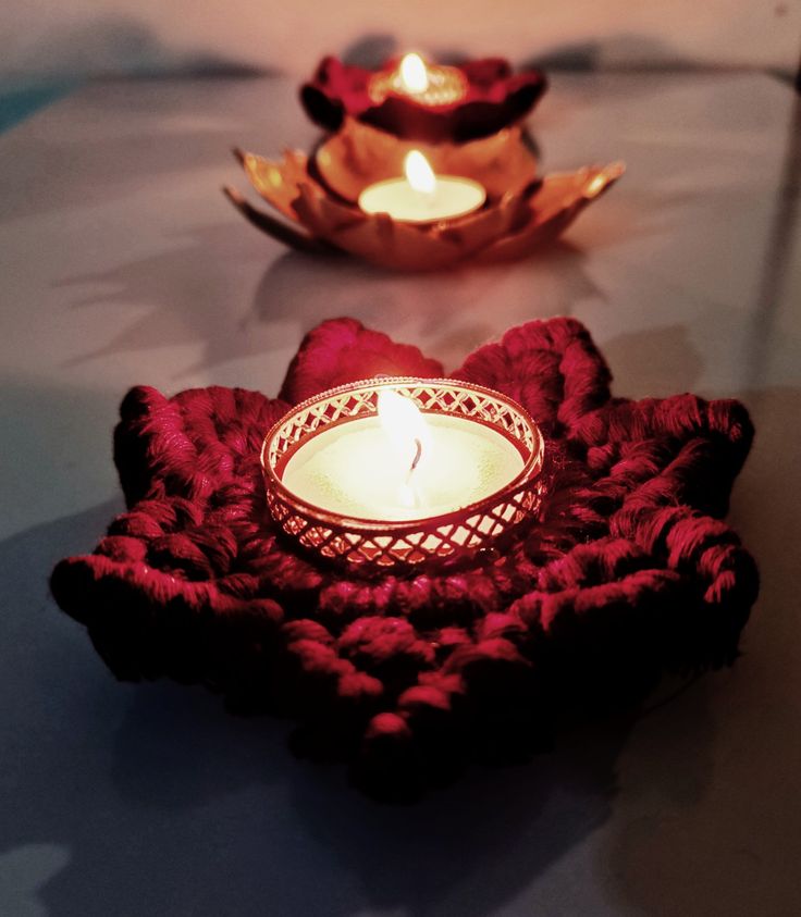 two lit candles sitting on top of a red doily next to a gold plate