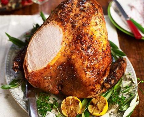 a roasted turkey on a plate with lemons and herbs