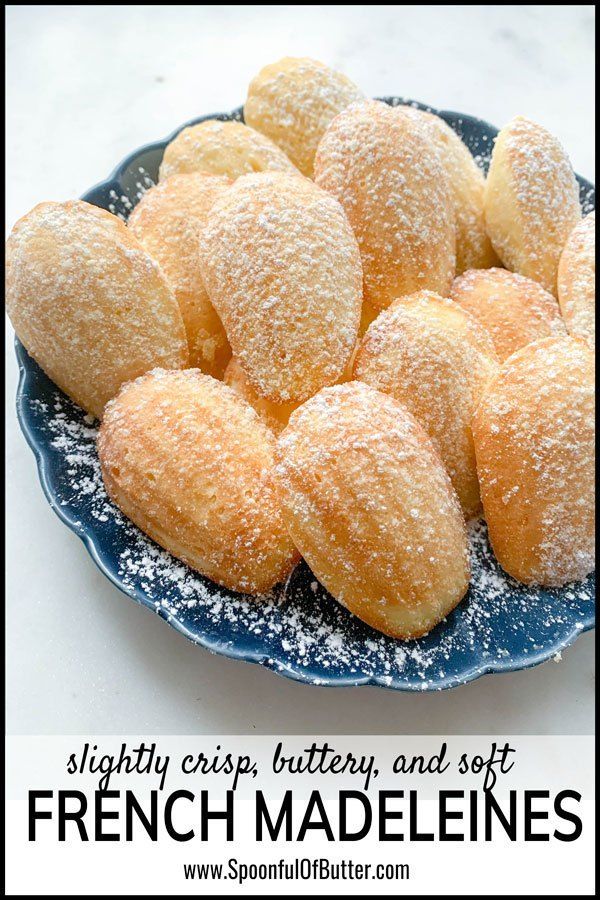 a blue plate filled with powdered sugar covered doughnuts on top of a white table