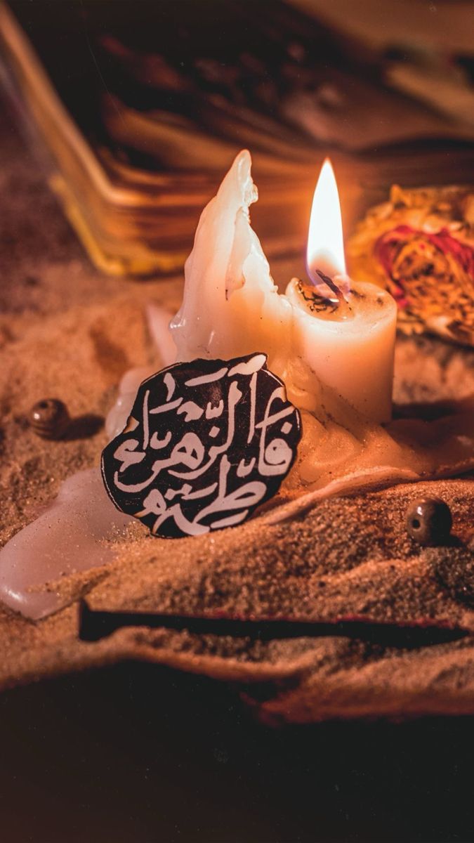 two lit candles sitting on top of sand