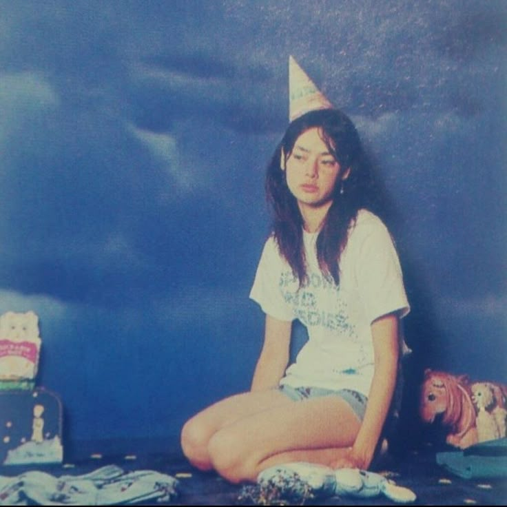 a young woman sitting on the floor wearing a party hat