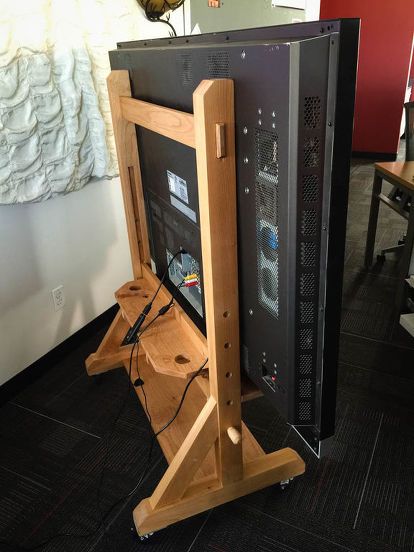 a wooden computer case sitting on top of a black floor in front of a monitor