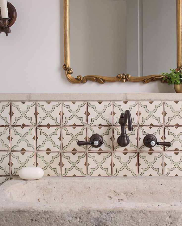 a bathroom sink sitting under a large mirror next to a wall mounted faucet