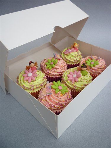 a box filled with cupcakes covered in pink and green frosted icing