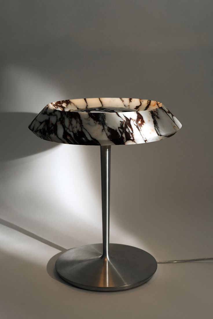 a lamp that is sitting on top of a metal base with a marbled shade