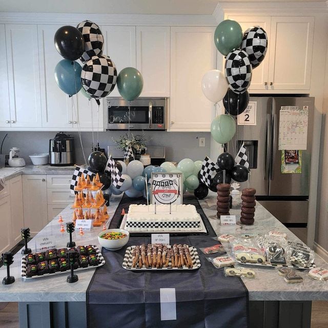 a birthday party with balloons, cake and desserts on the kitchen counter top in front of an oven