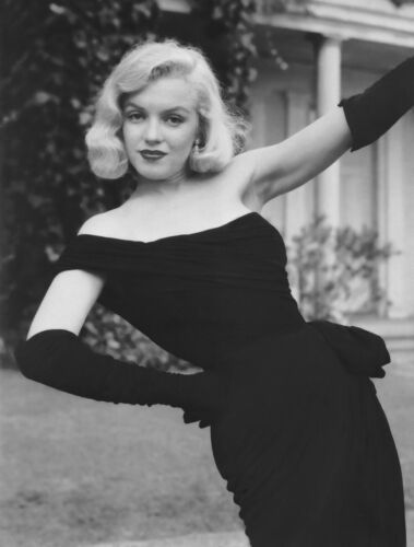 a black and white photo of a woman in a dress posing with her arms outstretched