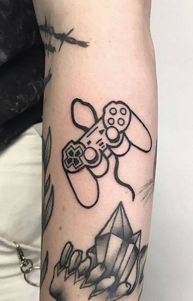 a person with a tattoo on their arm holding a video game controller