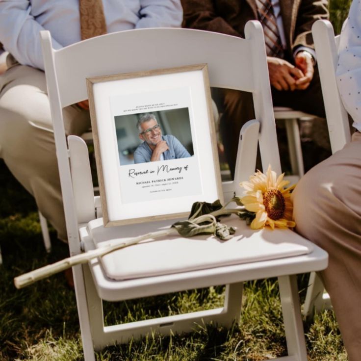 a white chair with a yellow sunflower sitting on top of it next to two men