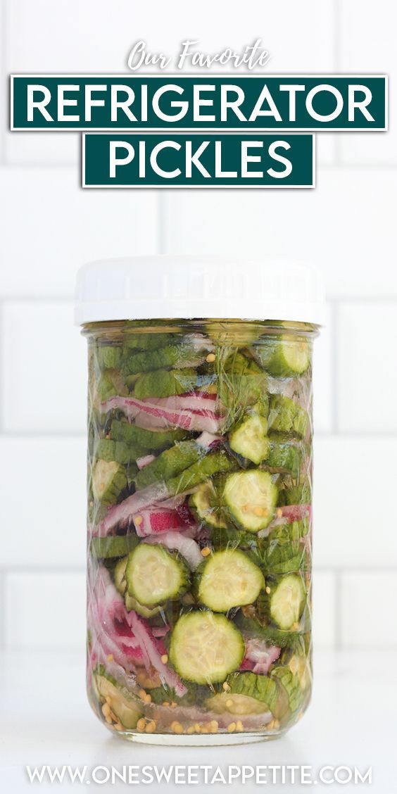 a glass jar filled with pickles and onions on top of a white tiled counter