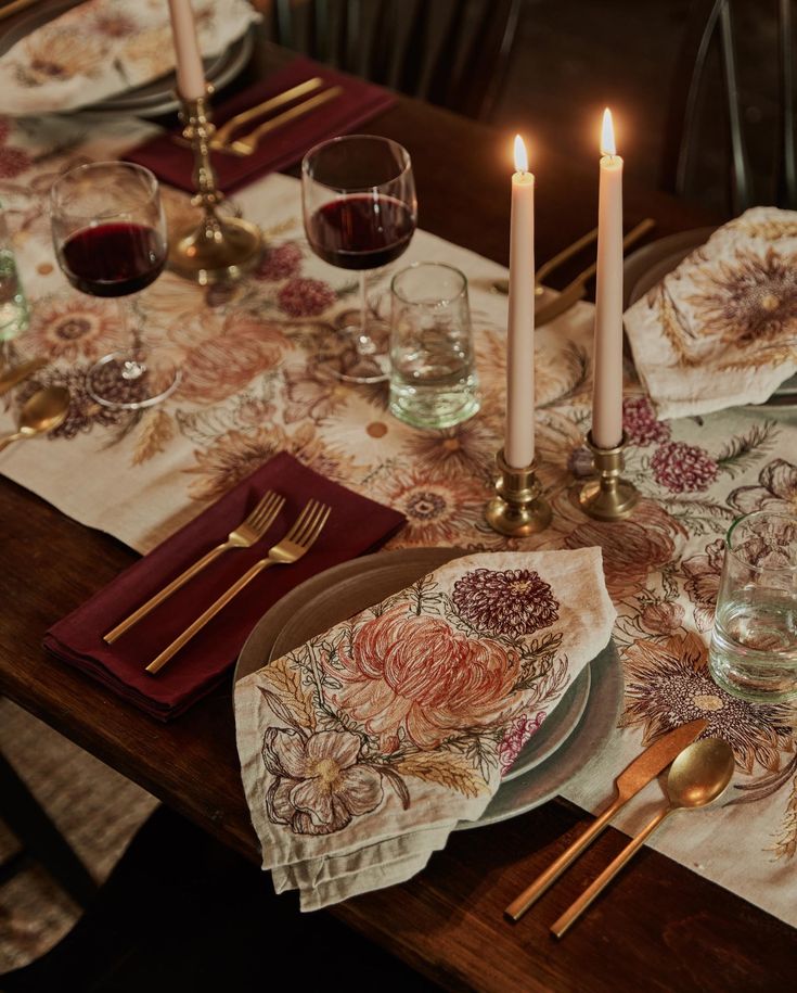 a table set with place settings, candles and napkins on top of the table