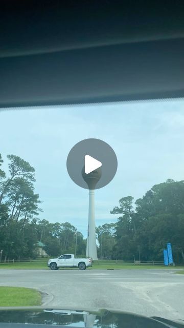 a white car driving down a street next to a tall tower