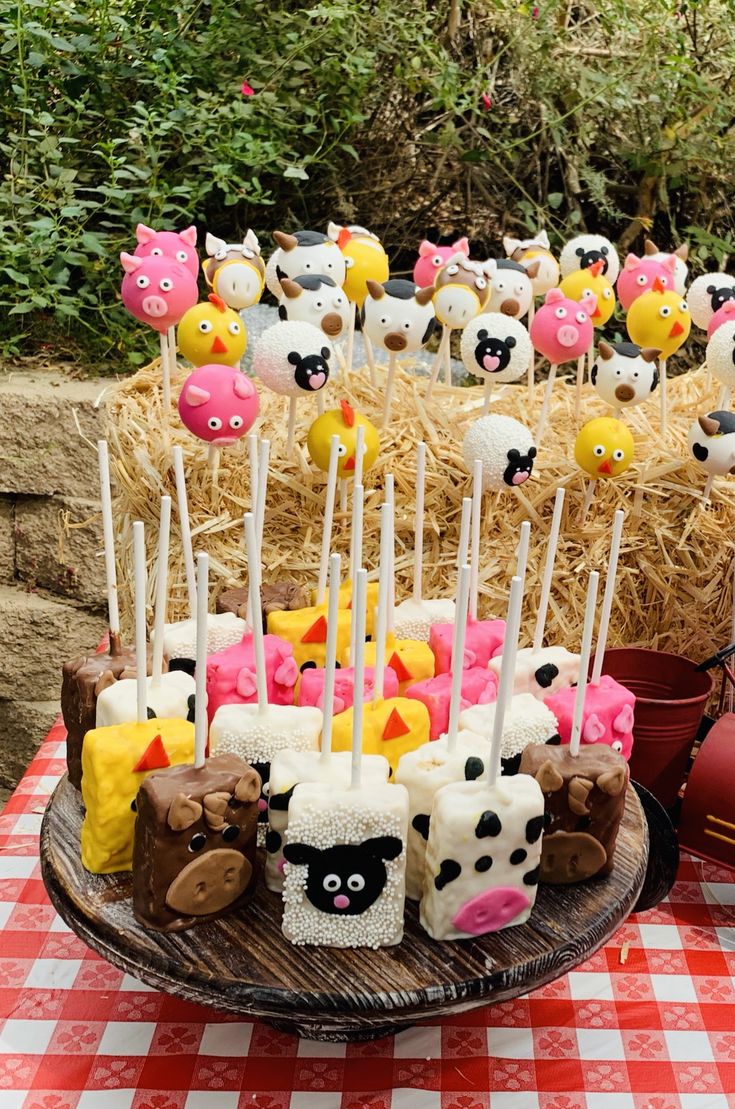 a table topped with cake pops covered in frosting and farm animals on top of them