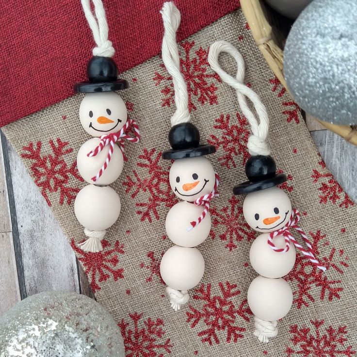 three snowmen are hanging from string on the table