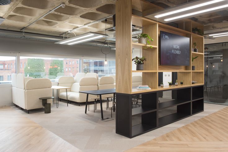 an office with chairs, desks and a flat screen tv in the middle of it