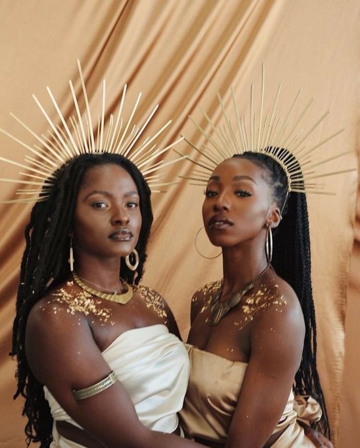 two women in white dresses standing next to each other with gold decorations on their heads