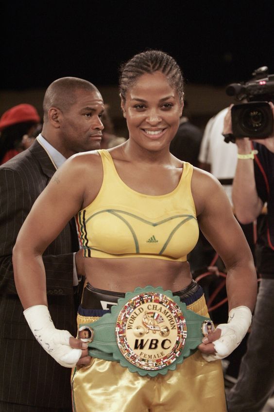 a woman standing next to a man holding a boxing belt