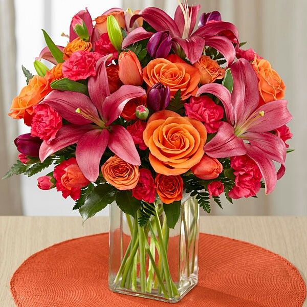 a vase filled with lots of orange and pink flowers