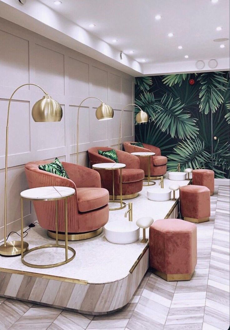 a room filled with lots of pink chairs and gold tables in front of a wall