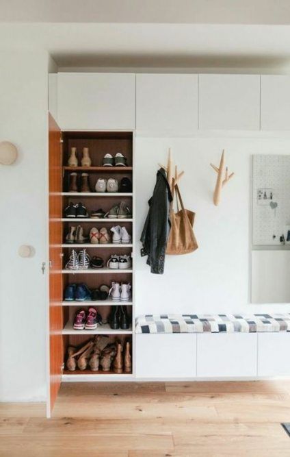 shoes are lined up against the wall in this white room with wooden flooring and built - in shelves