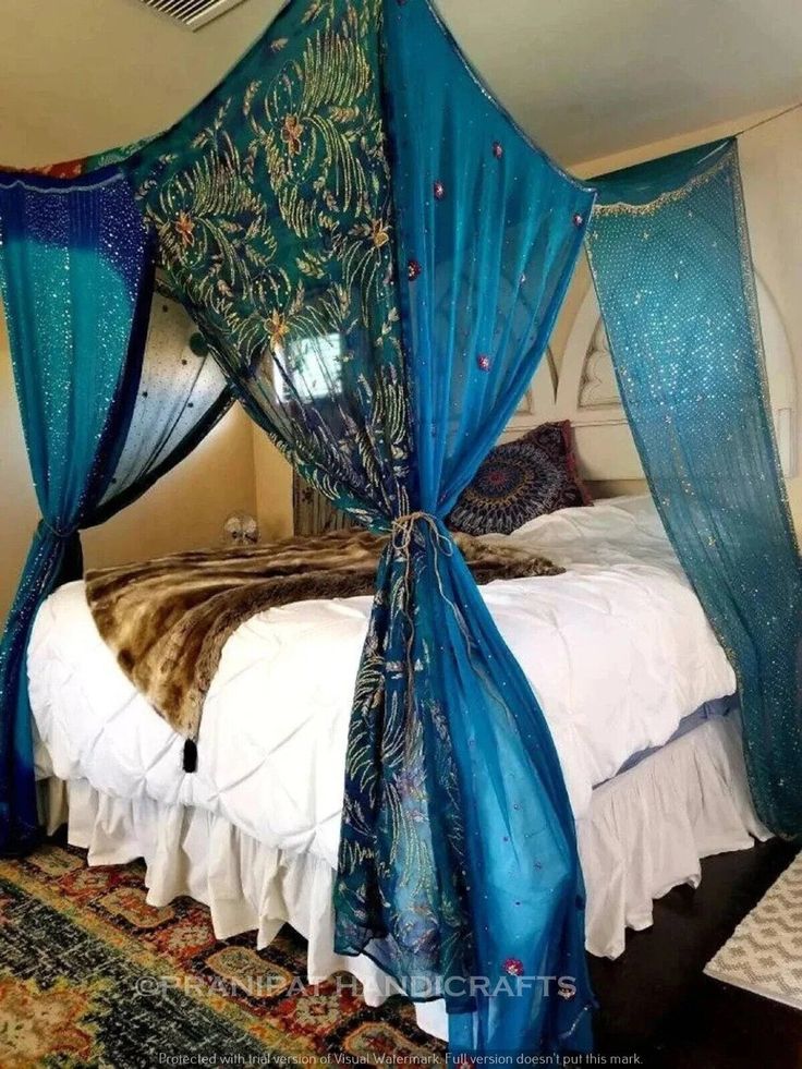 a canopy bed with blue drapes on it's headboard and foot board