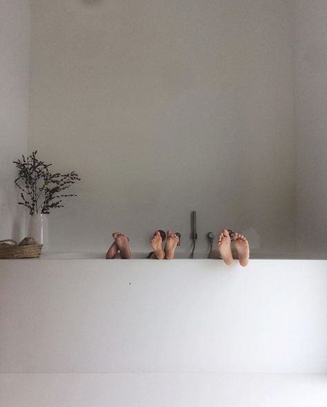 there are three pairs of bare feet on the ledge in front of a potted plant