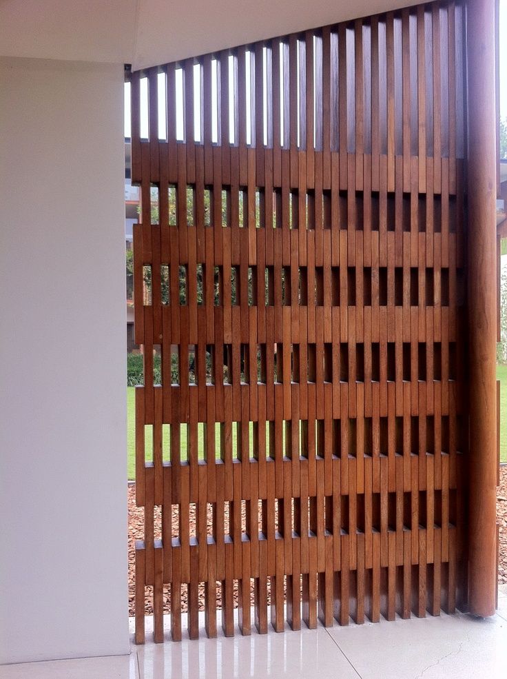 a wooden fence with vertical slats on the sides and an open window behind it