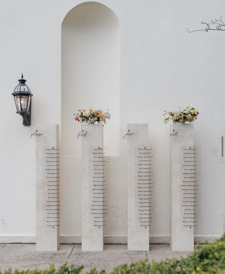 four cement urns with flowers on them are lined up against a wall in front of a lamp post